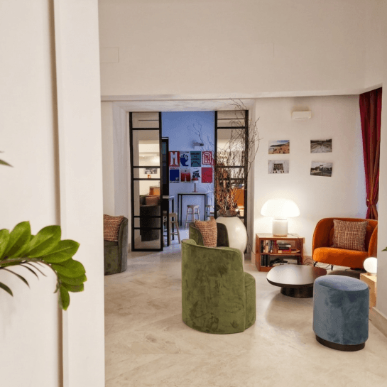 Lounge area with chairs, coffee table, lamp, and visible room beyond.