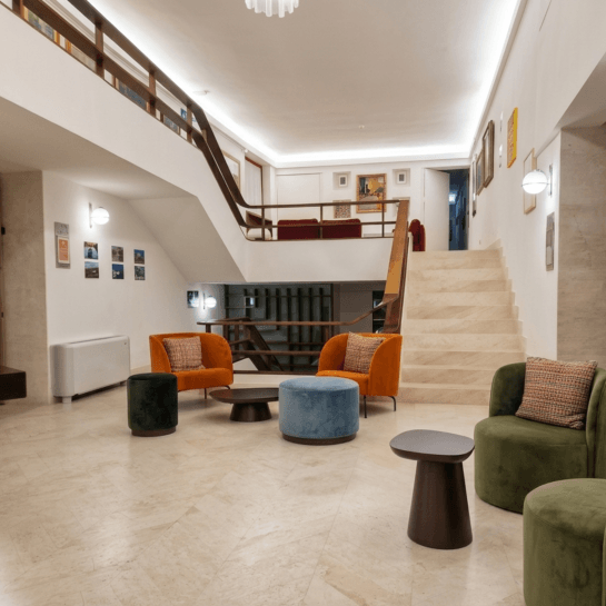 Spacious lobby with staircase, seating areas, and artwork on walls.