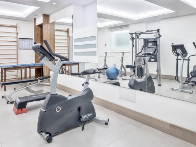 Modern exercise room with various equipment, including a stationary bike, treadmill, and blue exercise ball, plus a large mirror.