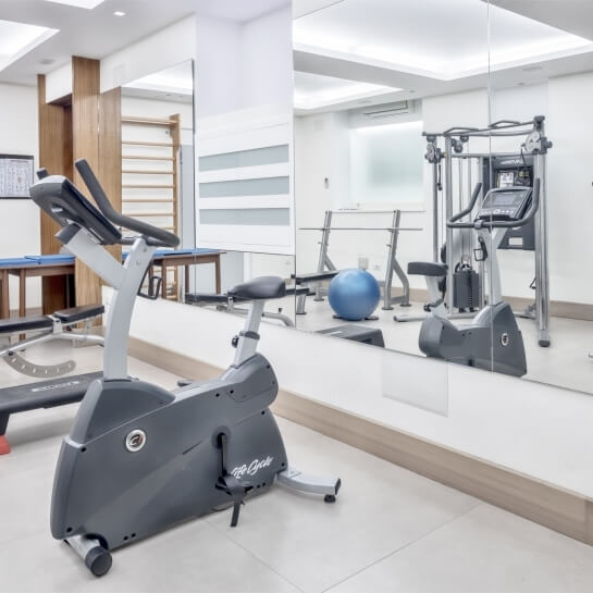 Palestra ben attrezzata con attrezzi, specchi e una palla da esercizio blu in un ambiente pulito e organizzato.