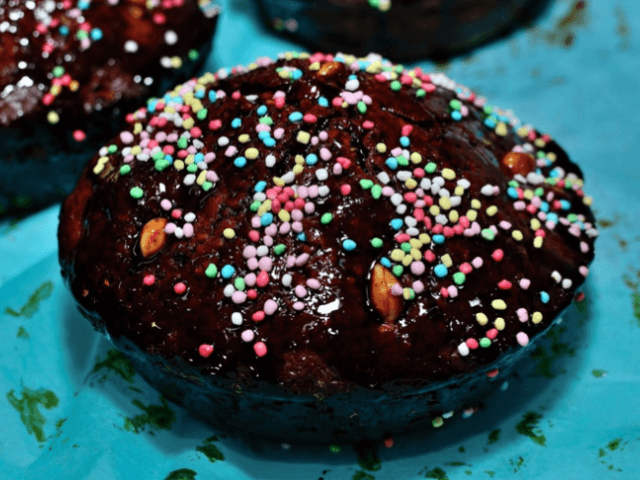 Due dolci glassati marroni con sprinkles colorati, uno in primo piano e l'altro parzialmente visibile sullo sfondo.