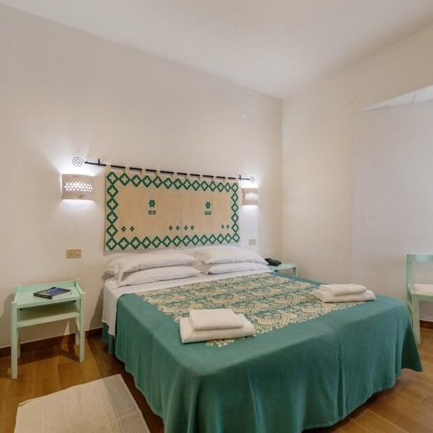 Camera da letto serena con letto teal, tappeto crema, arazzo elegante e atmosfera accogliente.