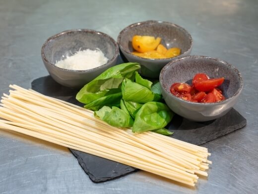 Un mazzo di pasta secca con ingredienti freschi e formaggio.