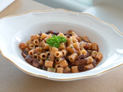Pasta con funghi in una ciotola bianca decorata.