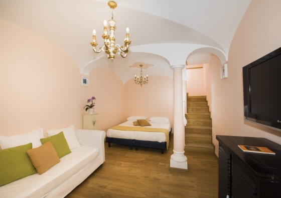 Camera d'hotel con divano, letto, televisore e scale in legno.