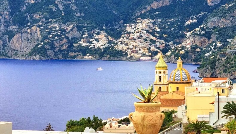 Coastal town on mountainside with colorful buildings and blue water.