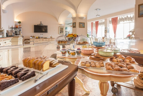 Buffet featuring assorted pastries, cakes, and bread with kitchen appliances.
