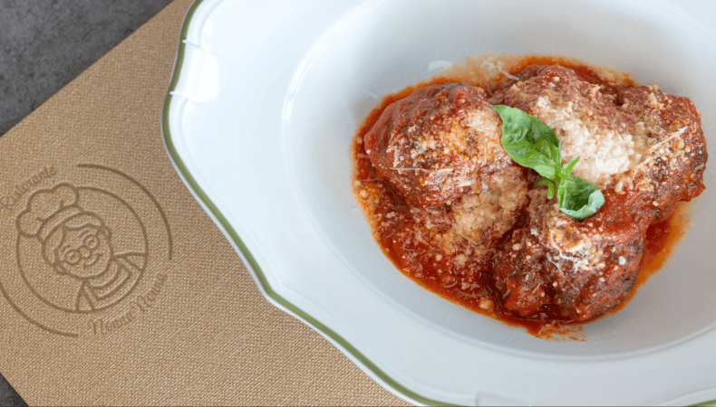 Bowl of meatballs in tomato sauce with cheese and basil.