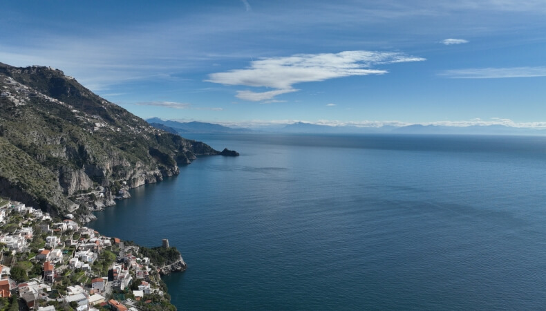 Coastal village on a green mountainside overlooking blue water.