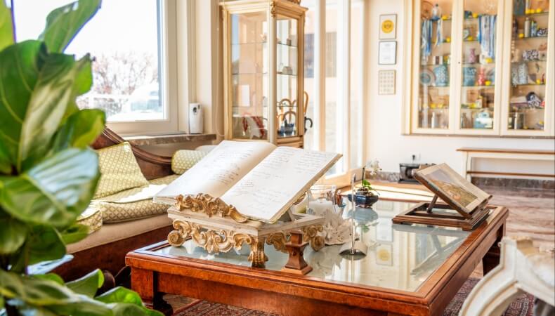 Open books on a coffee table with a couch and plant nearby.