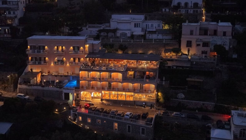 Night view of a multi-story building with balconies and a pool.