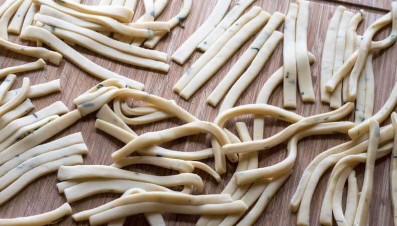 Un mucchio di spaghetti crudi su una superficie di legno.