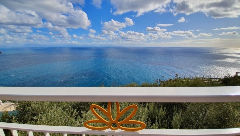 Acqua blu sotto nuvole bianche, con ringhiera bianca e ornamento giallo.