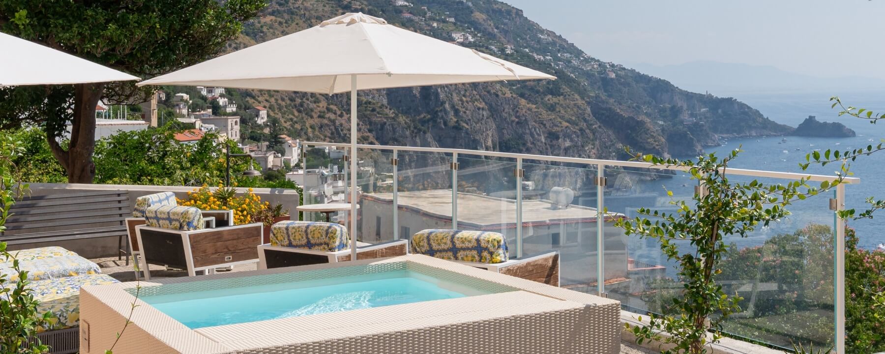 Outdoor patio with a hot tub, lounge chairs, and coastal view.