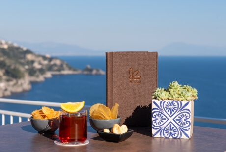 Brown menu on table with drink, snacks, and succulent; coastal town view.