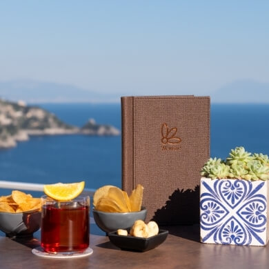 Table setting with menu, drink, snacks, and succulents by water.