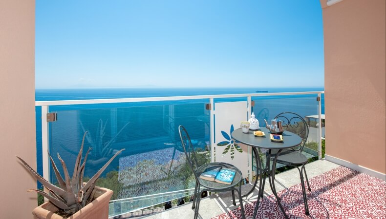 Balcone con tavolo, sedie, tea set, cibo e libro.