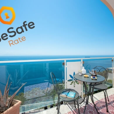 Balcony scene with table, chairs, teapot, book, and ocean view.