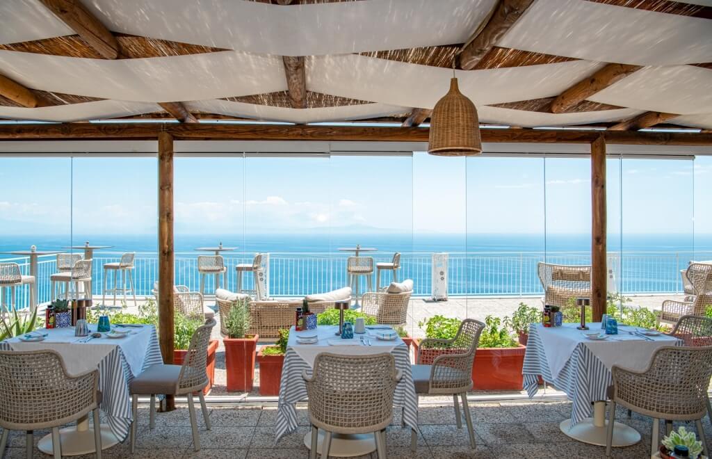 Area pranzo all'aperto con vista sull'oceano e tavoli decorati.