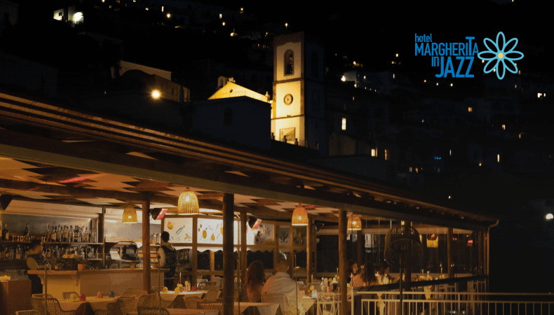 Nighttime outdoor restaurant with illuminated buildings and church tower.