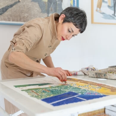 Woman in a jumpsuit drawing a colorful landscape with pastels.