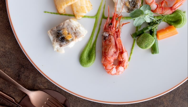 Piatto di frutti di mare con gambero, pesce e purè verde.