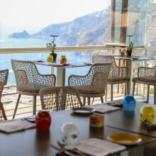 Outdoor dining area with tables, colorful cups, and a scenic water view.