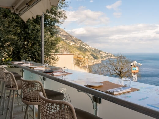 Area pranzo all'aperto con vista mare e tavoli apparecchiati.