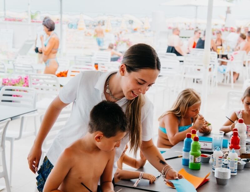 Donna aiuta un ragazzo con un'attività artistica all'aperto.