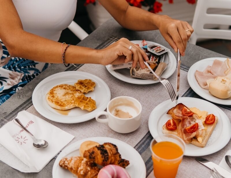 Breakfast spread with Mickey Mouse pancakes, waffles, and coffee at Rizza Hotel.