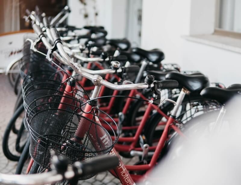 Row of red bicycles with black baskets and seats.