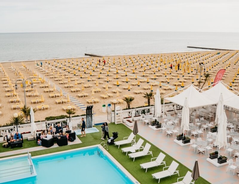 Beach scene with yellow lounge chairs, umbrellas, and a pool.