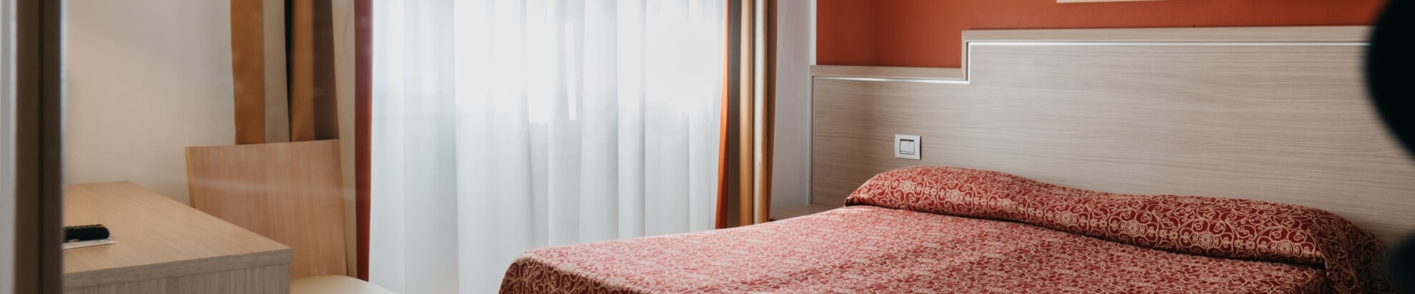 Camera d'hotel con letto, scrivania e parete arancione.