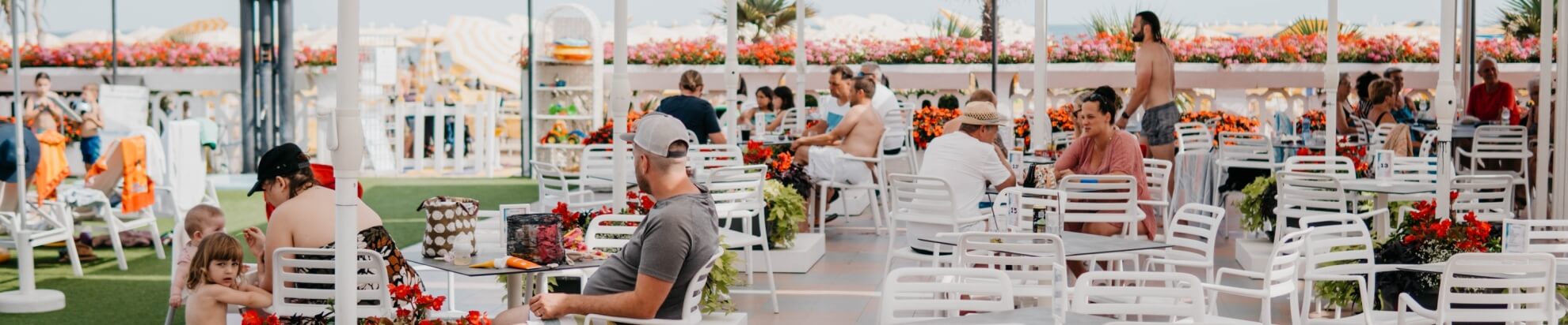 Outdoor seating area with flowers, children, and beach umbrellas.