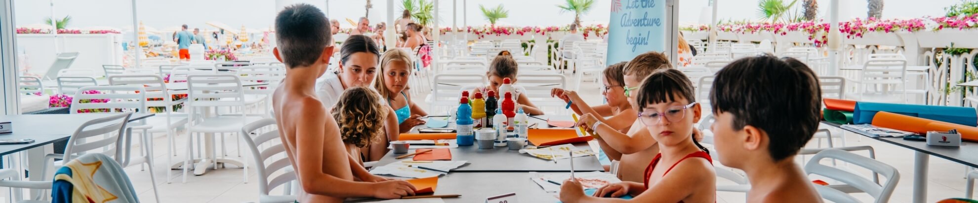 Kinder malen an einem Tisch mit Kunstmaterialien im Freien.