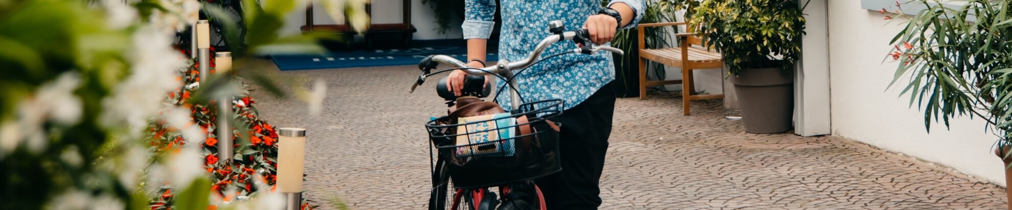 Person with a bicycle and basket, holding a city map outdoors.