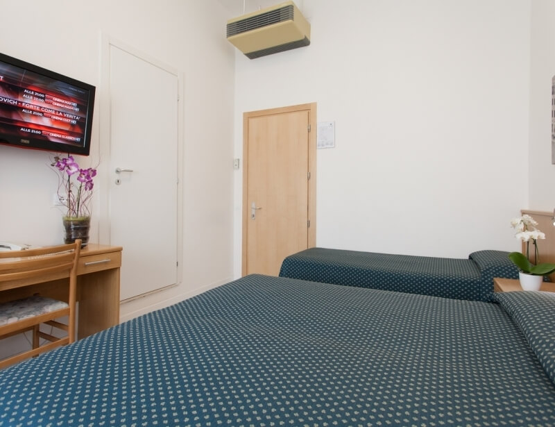 Hotelzimmer mit zwei Betten, Schreibtisch, Fernseher und Klimaanlage.