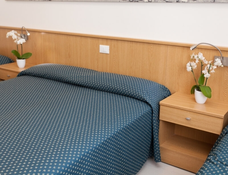 Hotelzimmer mit zwei Betten, Orchideen und silbernen Leselampen.