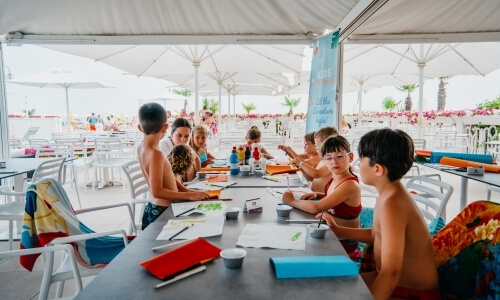 Bambini fanno attività artistiche all'aperto con materiali vari.