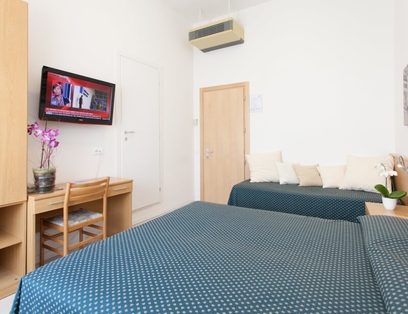 Camera d'hotel con due letti, scrivania e TV a schermo piatto.