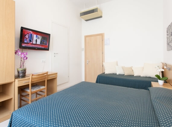 Camera d'hotel con due letti, TV, scrivania e armadio.