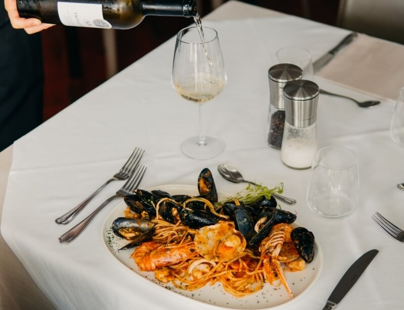 Piatto di spaghetti con frutti di mare e vino bianco.