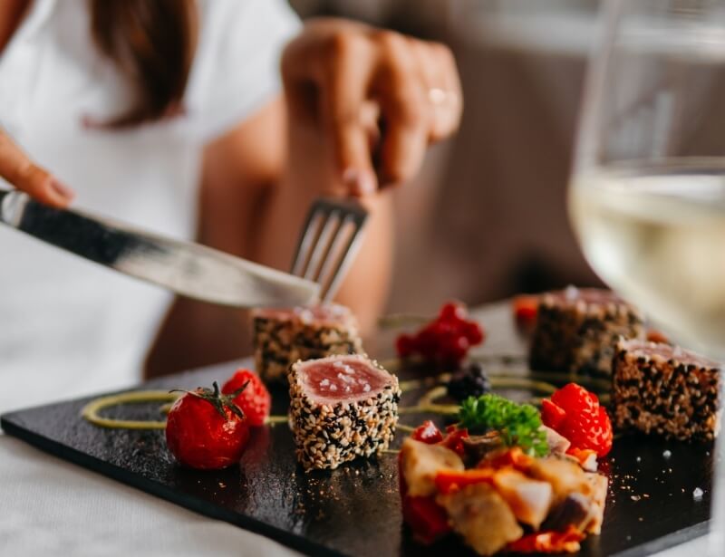 Cubetti di tonno croccante con pomodorini e fragole su piatto scuro.