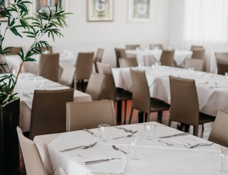 Area pranzo con tavoli apparecchiati e opere d'arte sullo sfondo.