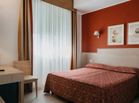 Camera d'hotel con letto, scrivania e decorazioni murali.