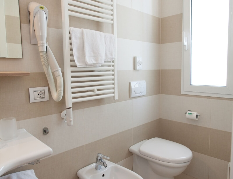 Bagno d'hotel con toilette, bidet, asciugacapelli e asciugamani.