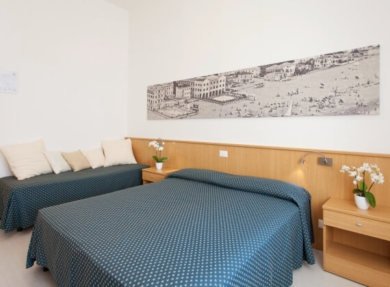 Camera d'hotel con due letti, daybed e panorama di spiaggia.