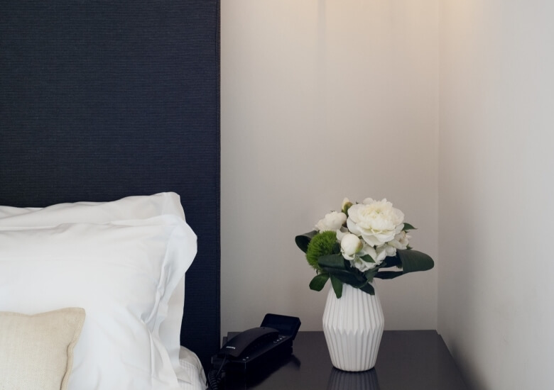 black bedside table with vase and white roses 