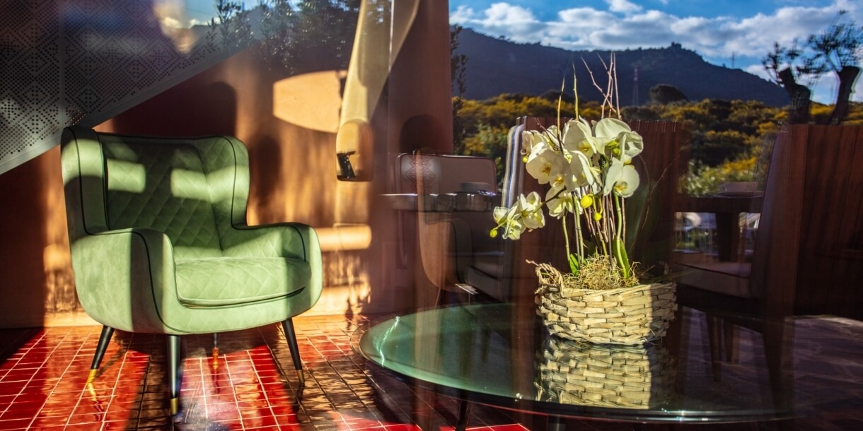 Dettaglio salotto con poltrona in tessuto verde e orchidea