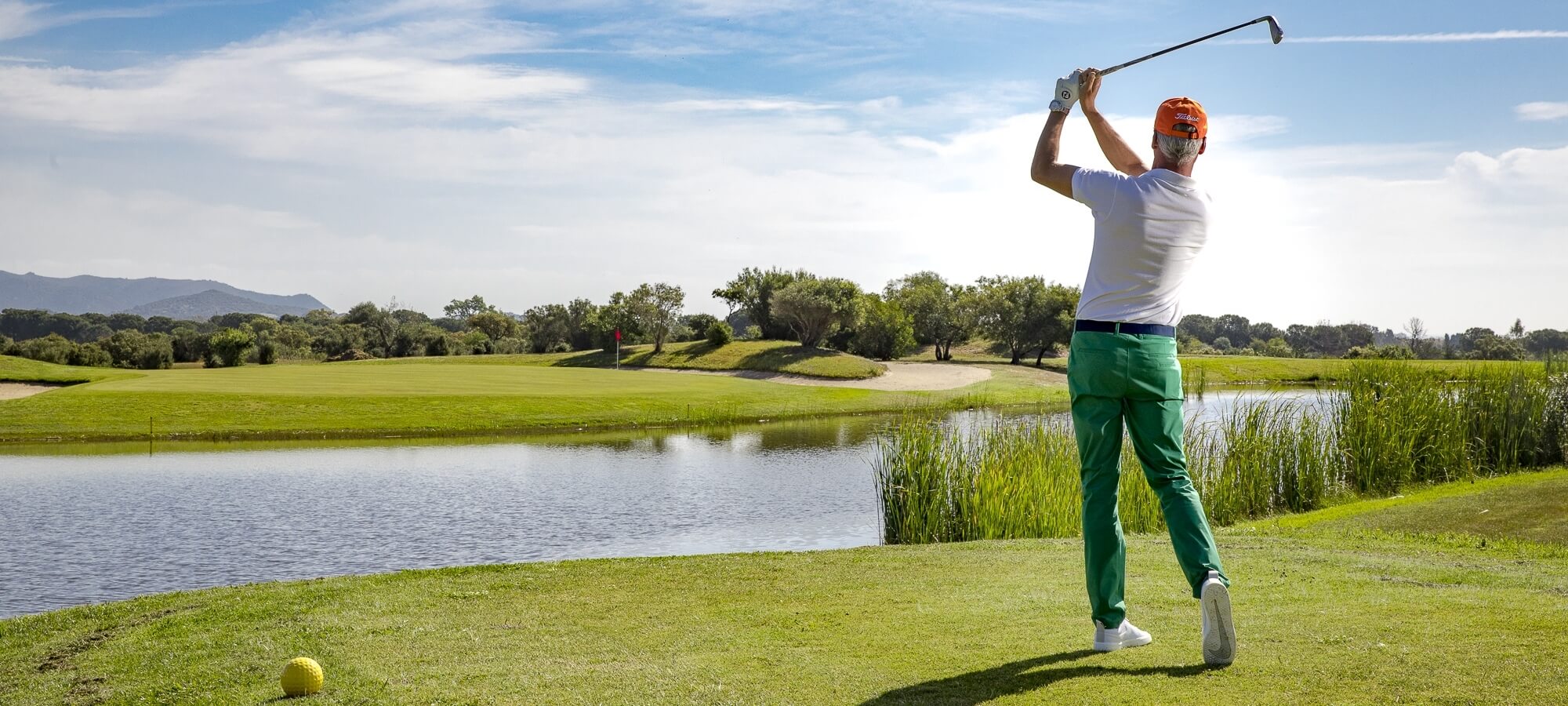 Uomo che lancia davanti al laghetto in campo da golf